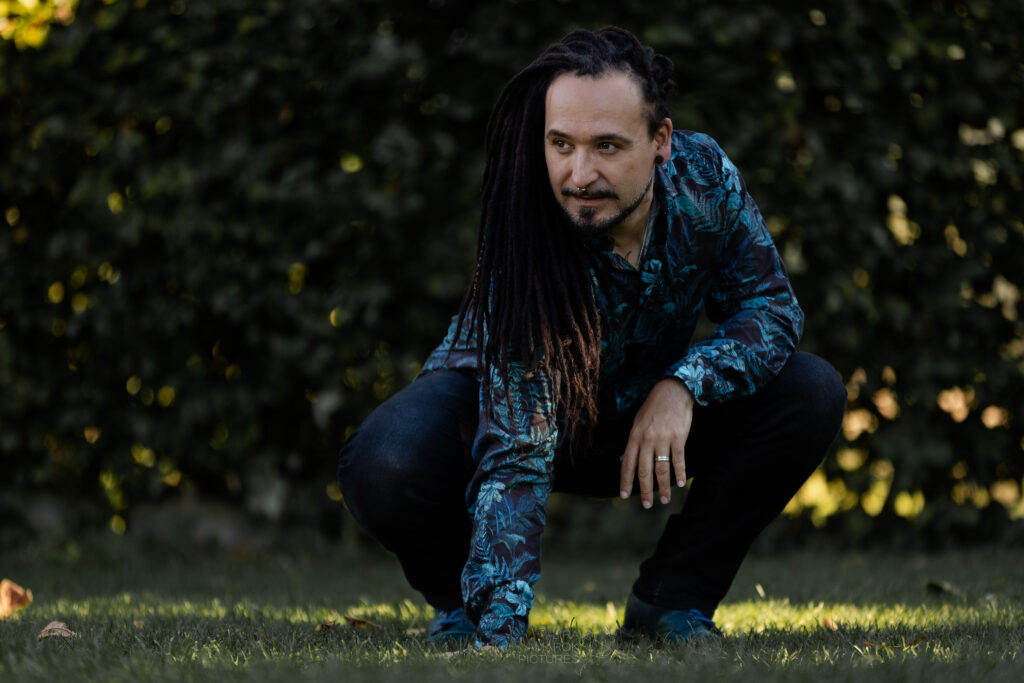 Ein Mann mit Dreadlocks kniet am Boden und sieht zur Seite