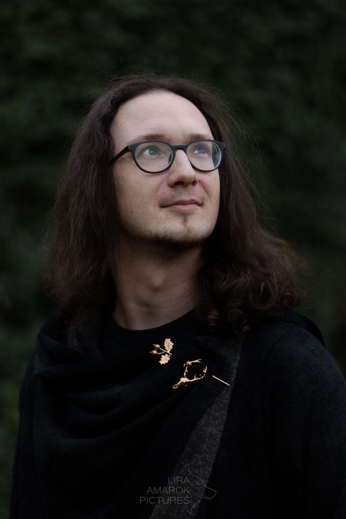 aufsehend Portrait eines Mannes der nach oben sieht. Er trägt am Gewand eine Hirschbrosche