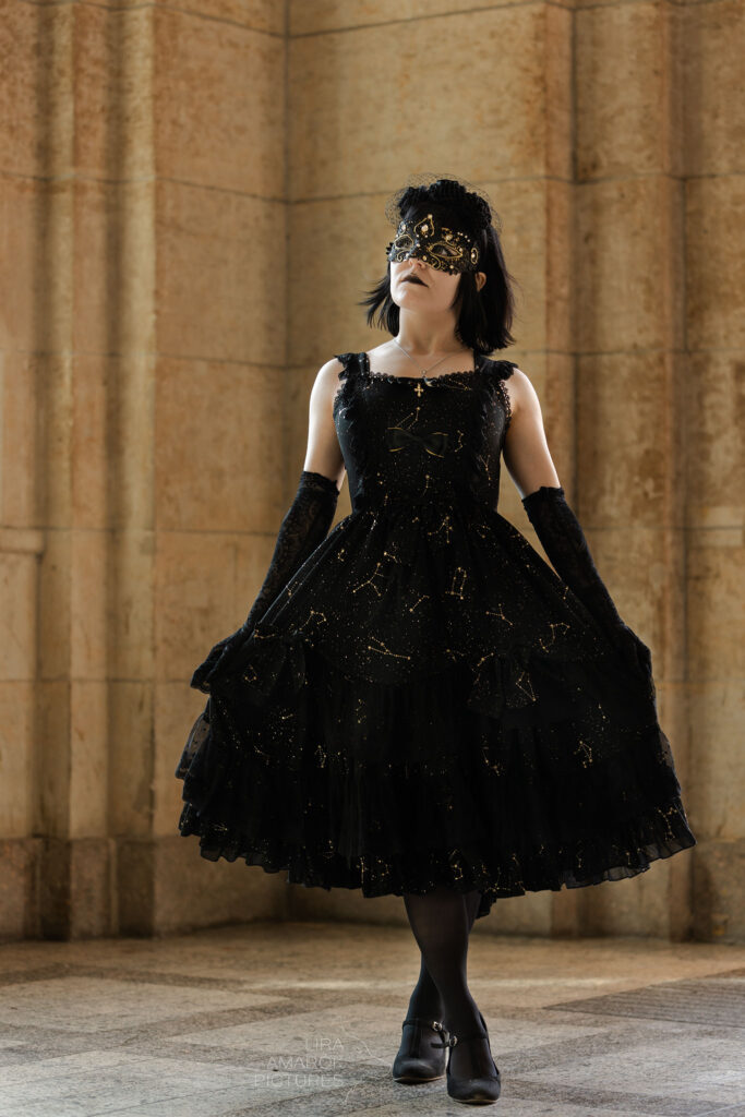 Show me Frau steht vor Säulen im Kleid mit Maske